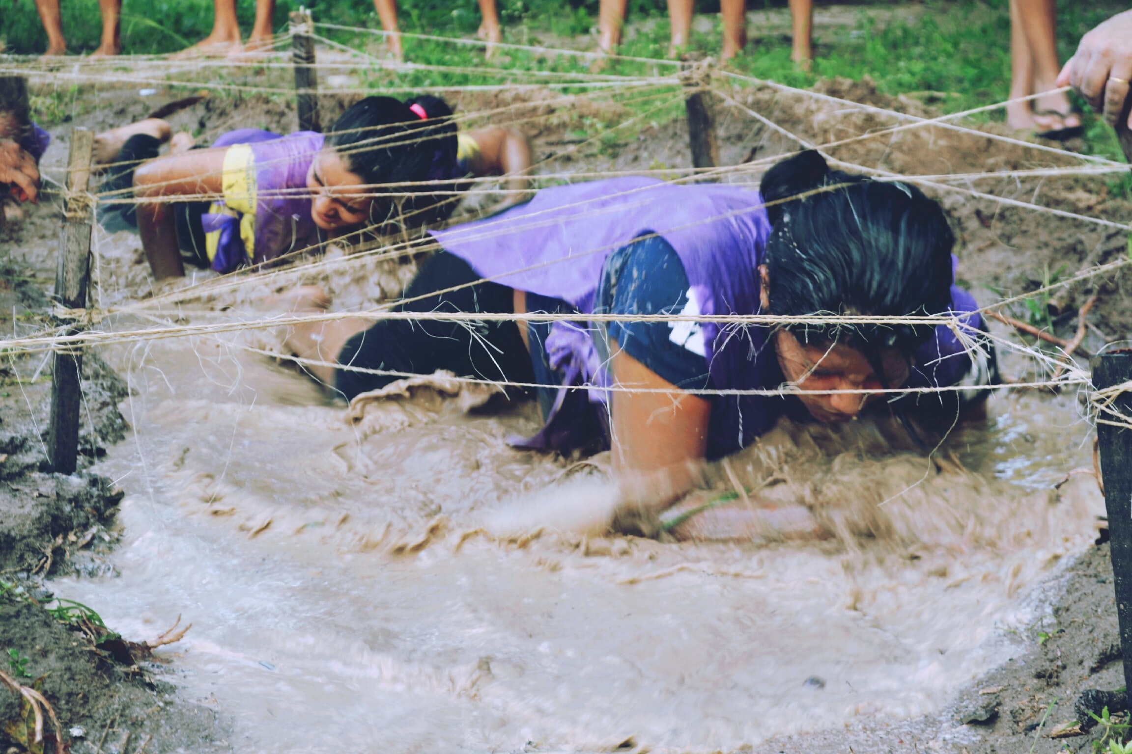 Person crawling through mud as part of a challenge